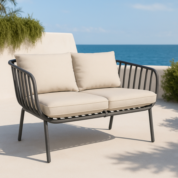 Sillón de exterior Banús de una plaza en color grafito con cojines beige sobre terraza con vistas al mar