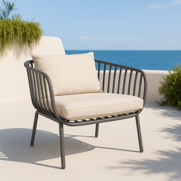 Sillón de exterior Banús de una plaza en color grafito con cojines beige sobre terraza con vistas al mar